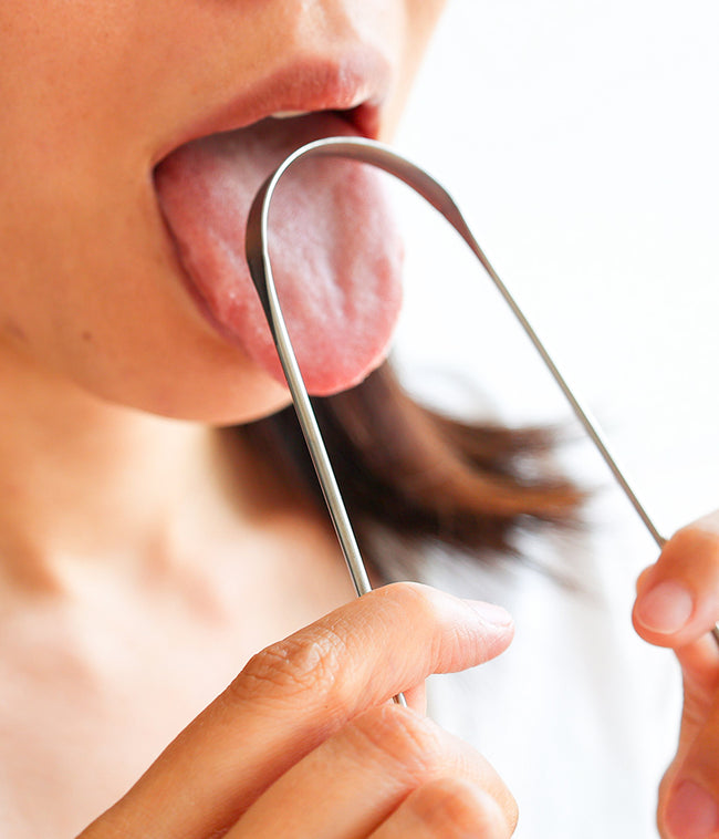 舌みがきを舌にあてる女性